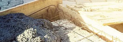 Frischer Beton und eine Kelle in einer quadratischen Schalung.